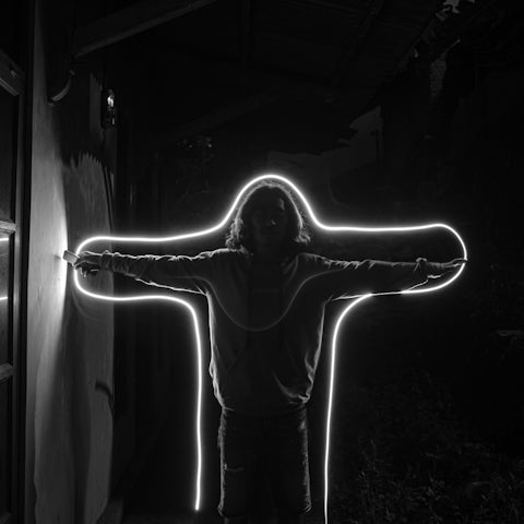 grayscale photo of woman in black long sleeve shirt and pants standing in front of light