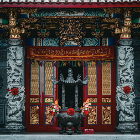 a red and gold building with a black vase in front of it