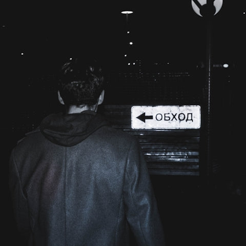 A person walks toward a sign at night.